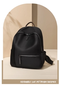 Detail van minimalistische zwarte nylon rugzak met bruin lederen handvat en zilveren rits