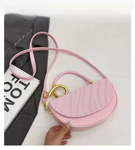 Detailed view of pink leather saddle bag with wave texture and gold metal ring handle