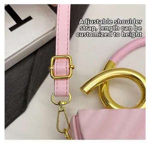 Detail of pink saddle bag featuring adjustable leather strap and golden circular metal handle