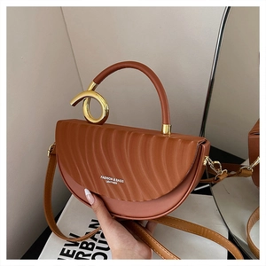 Close-up of brown crescent saddle bag featuring wavy texture and golden twist handle