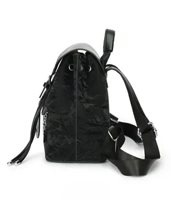 Detailed side view of black shiny pleated backpack with leather handle and drawstring metal eyelets
