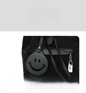 Detail of a black textured backpack featuring a round smiley face charm and silver clasp