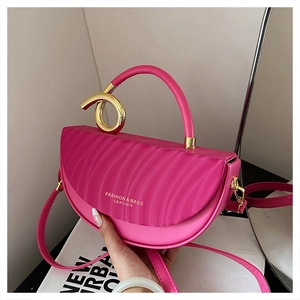 Detail of rose red saddle bag with artistic gold metal handle and adjustable strap