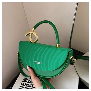 Detail of vibrant green saddle bag with unique gold ring hardware and leather texture