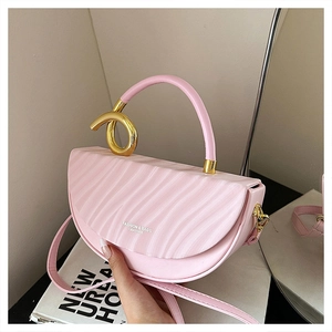 Pink saddle bag featuring wavy texture and a golden metal ring handle detail on a magazine