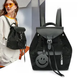 Detail view of black pleated nylon backpack with flap closure and smiley face charm