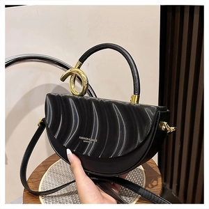 Detail of black leather saddle bag featuring unique 3D wavy texture and golden metal hardware