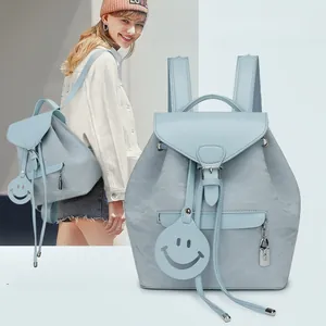 Detail showing blue wrinkled texture fabric and hollow smiley face charm on backpack