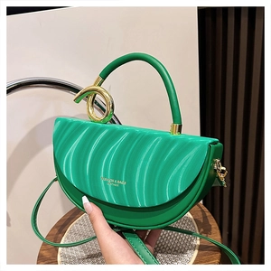 Detail of bright green crescent bag featuring unique wavy embossing and gold knot hardware