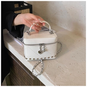 Dettaglio della mini borsa a scatola trapuntata in vernice bianca con borchie argento