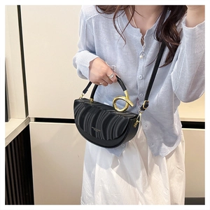 Detail of black pleated leather half-moon bag with elegant gold twisted metal handle