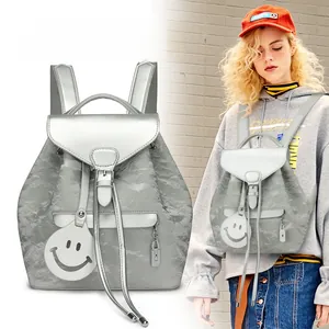 Detailed close-up of metallic silver backpack with crinkled texture and cute smiley pendant