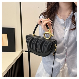Detail of black pleated crescent handbag featuring a twisted gold metal handle and logo