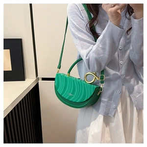 Detail of green half-moon saddle bag with wavy flap design and gold ring handle