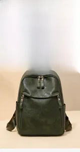 Detail view of a vintage dark green backpack with dual zippers and textured leather