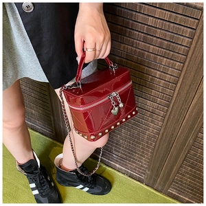 Dettaglio mini borsa in vernice trapuntata rosso scuro con borchie dorate e zip a cuore