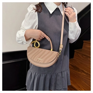 Detail of light brown semi-circle leather bag with gold spiral handle and wavy texture