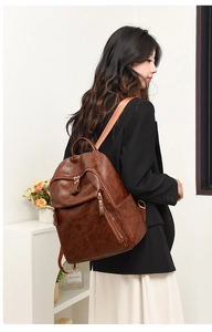 Retro brown PU leather backpack detail with multiple zipper pockets on a female model
