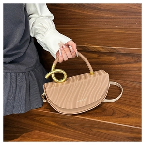 Detail of light khaki saddle bag with wavy texture and golden spiral metal handle