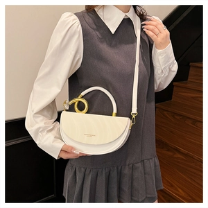 Detail of white moon saddle bag with gold spiral metal rings and branding text