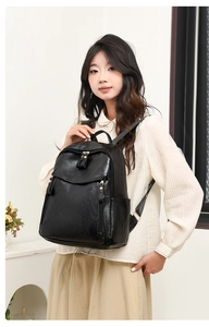 Detail view of black vintage backpack with gold hardware worn by a model in casual attire