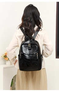 Detailed back view of a black pebble leather backpack with sturdy straps on a model