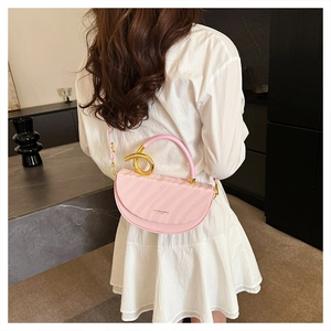 Detail of pink saddle bag with golden spiral handle and textured ripple finish