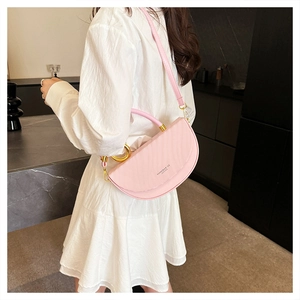 Detail of pink half-moon saddle bag with gold metal rings and adjustable leather strap