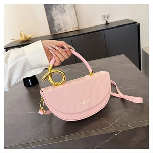 Detailed shot of pink saddle bag with golden spiral handle and leather texture