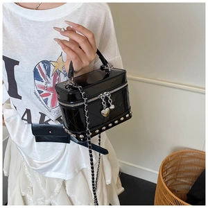 Dettaglio mini borsa in pelle verniciata nera trapuntata con borchie e ciondolo cuore