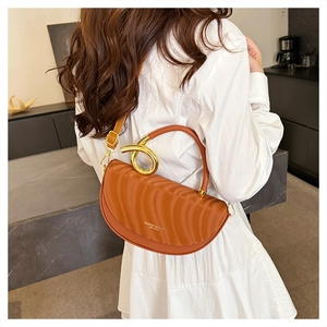 Detail of orange crescent bag with wavy texture and gold metal ring hardware on the strap