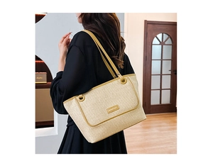 Detail of minimalist straw tote bag with mustard yellow leather trim and logo plaque