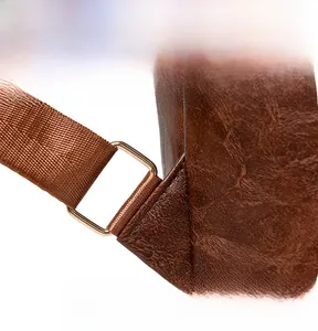 Detail of vintage brown leather texture and durable golden metal ring buckle on shoulder strap