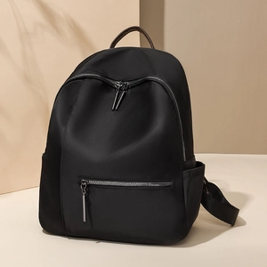 Minimalistische zwarte nylon rugzak met bruin lederen handvat en meerdere ritszakken