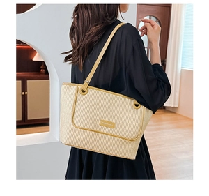 Detail of beige woven straw tote bag with yellow leather trim and logo patch