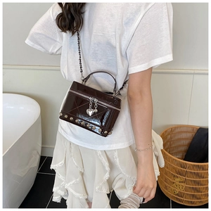 Dettaglio della mini borsa marrone in pelle verniciata con catena e ciondolo a cuore
