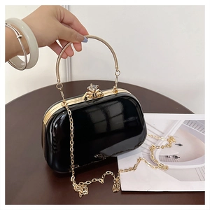 Detail of glossy black patent leather evening bag with gold handle and crystal clasp