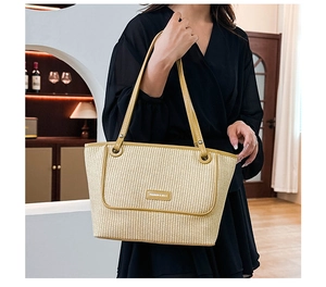 Detail of woven straw tote bag with contrasting olive green trim and fashion logo plate