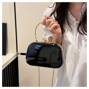 Detail of black patent evening bag with gold handle and diamond clasp ornament