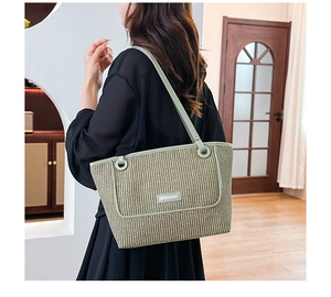 Detail of light green woven tote bag showing texture and circular metal strap hardware