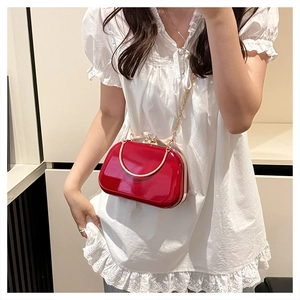 Detail of red patent leather crossbody bag with gold metal handle and chain strap