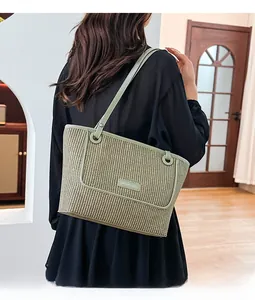 Close-up of green woven tote bag with leather logo tag on a casual shoulder display