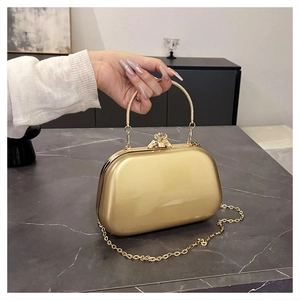 Macro detail of a gold oval clutch bag with gemstone clasp and metallic ring handle