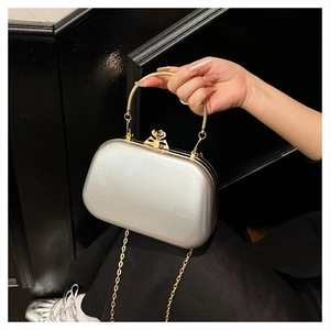 Detail of silver evening bag with a gold metal handle and large crystal clasp closure