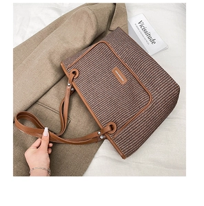 Detail of woven brown tote bag with leather texture and brand tag on blazer background