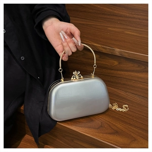 Close-up of a silver mirror evening bag with gold circular handle on wooden stairs