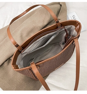 Detail view of woven brown tote bag featuring leather handles and internal zipper pocket