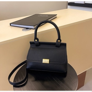 Dettaglio borsa a mano in pelle martellata nera con fibbia dorata in esposizione