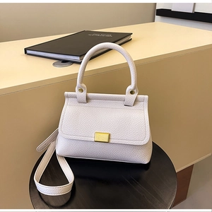 Dettaglio borsa in pelle martellata bianco crema con chiusura metallica dorata su vassoio