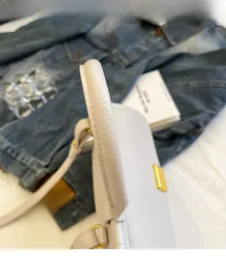 Dettaglio del manico in pelle martellata bianca con anelli dorati sulla borsa a mano